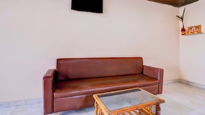 A brown leather sofa against a white wall with a small wooden table in front. - Hotel O Palava Dombivali (Mumbai)