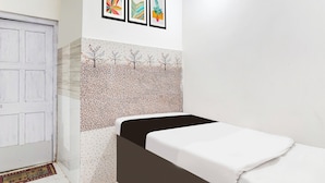 Een kamer met een bed, een witte deur en een muur met kunstwerken.
