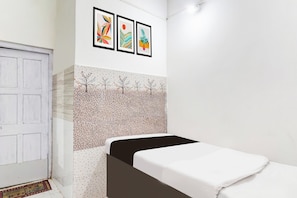 Ein Zimmer mit einem Bett, einer weißen Tür und einer Wand mit gerahmten Kunstwerken.
