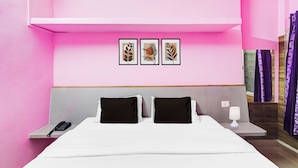 Een hotelkamer met een bed, twee nachtkastjes, een telefoon, een lamp en drie ingelijste kunstwerken aan de muur.