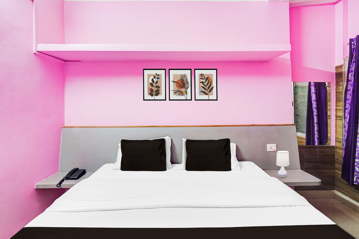 Ein Hotelzimmer mit einem Bett, zwei Nachttischen, einem Telefon, einer Lampe und drei gerahmten Kunstwerken an der Wand.