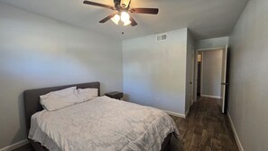 A bedroom with a bed, a nightstand, a ceiling fan, and a door leading to another room. - Spacious 3BR Home for a Houston Getaway (Houston)