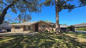 A single-story house with a brick facade, a front porch, and a lawn. - Spacious 3BR Home for a Houston Getaway (Houston)