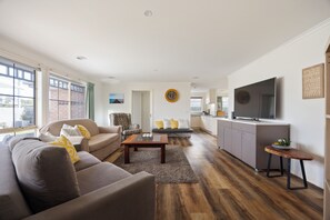 A modern living room with a sofa, armchairs, a coffee table, and a television. - Bimble Street Beach House - 300 Meters to beach & Pet Friendly (Melbourne)