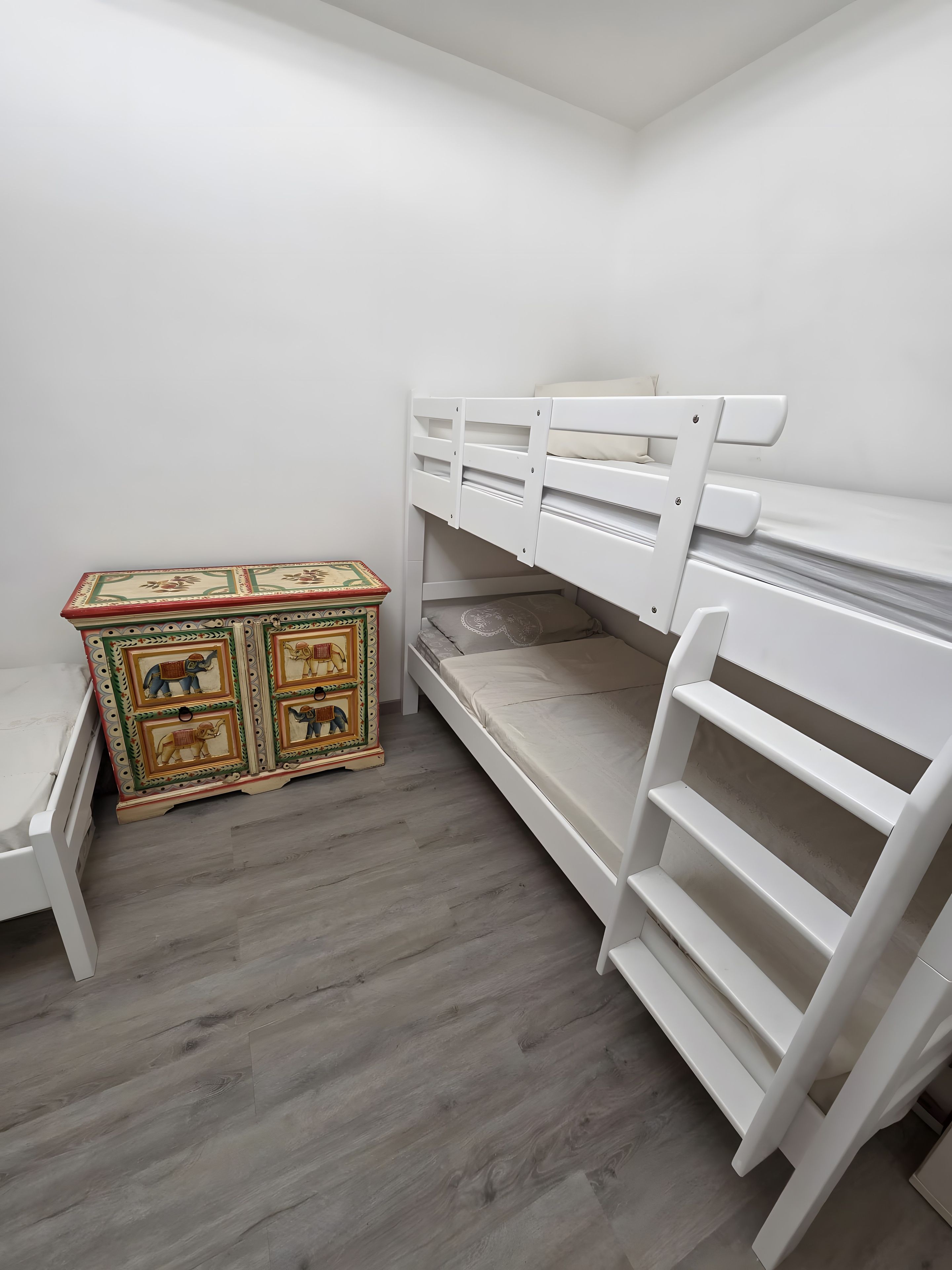 A child's bedroom with bunk beds, a small table, and a decorative chest.