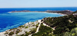Eine Küstenlandschaft mit freiem Blick auf das Meer, einem Sandstrand und felsigem Gelände.