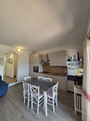 Um espaço de estar compacto com área de refeições, cozinha compacta e corredor que dá para outro quarto.