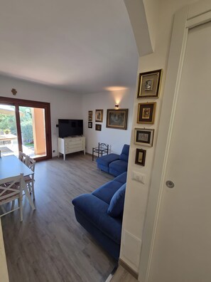 Uma sala de estar com sofá, televisão e um espaço de jantar com mesa e cadeiras.