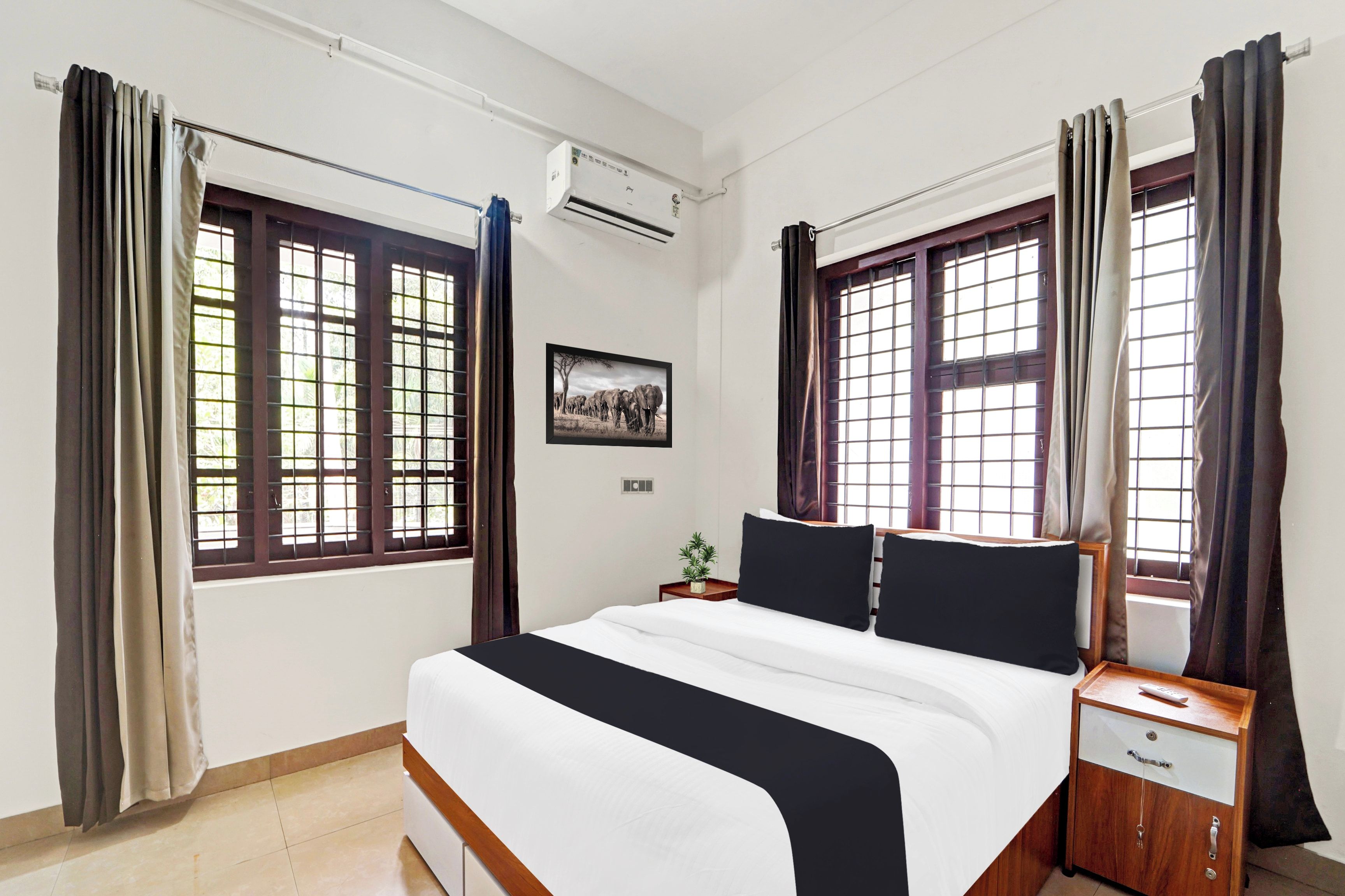 Una habitación de hotel con una cama grande, dos mesitas de noche, un ventilador y una ventana con cortinas.