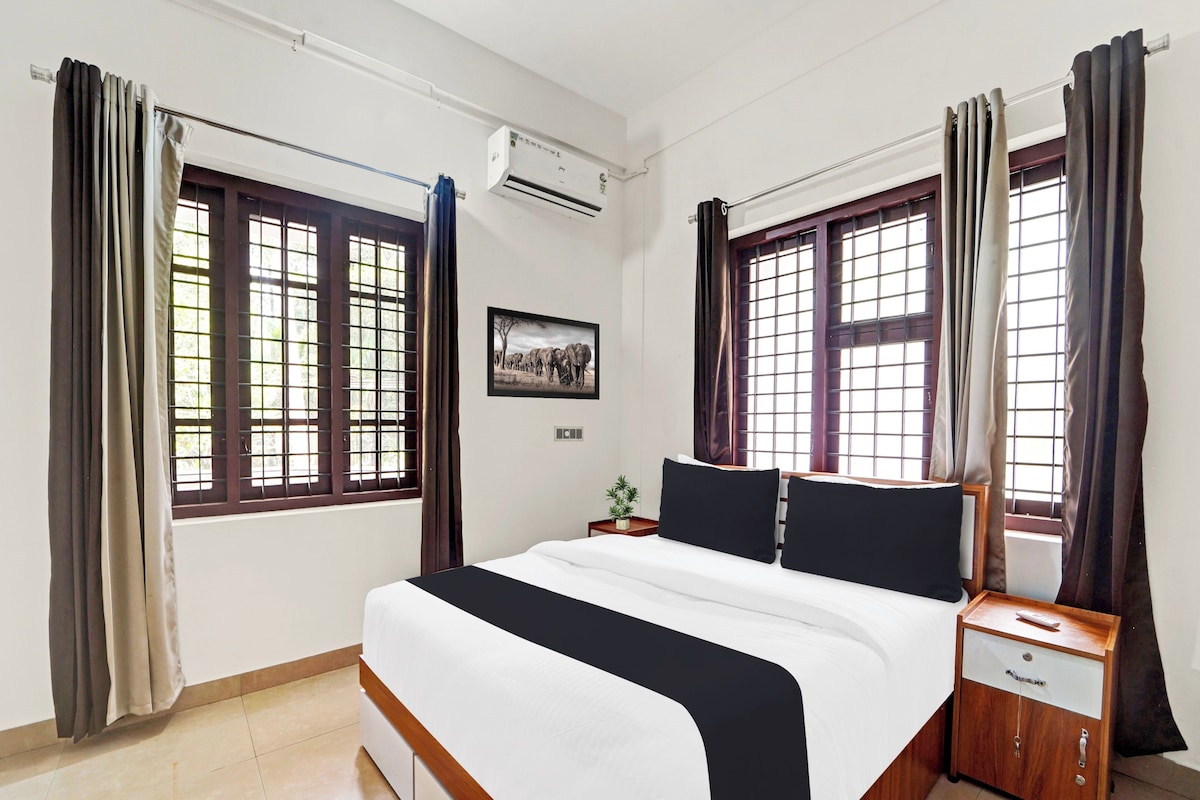 Una habitación de hotel con una cama grande, dos mesitas de noche, un ventilador y una ventana con cortinas.