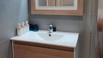 Une salle de bain avec un lavabo blanc, un meuble-lavabo en bois et un miroir avec un cadre en bois.