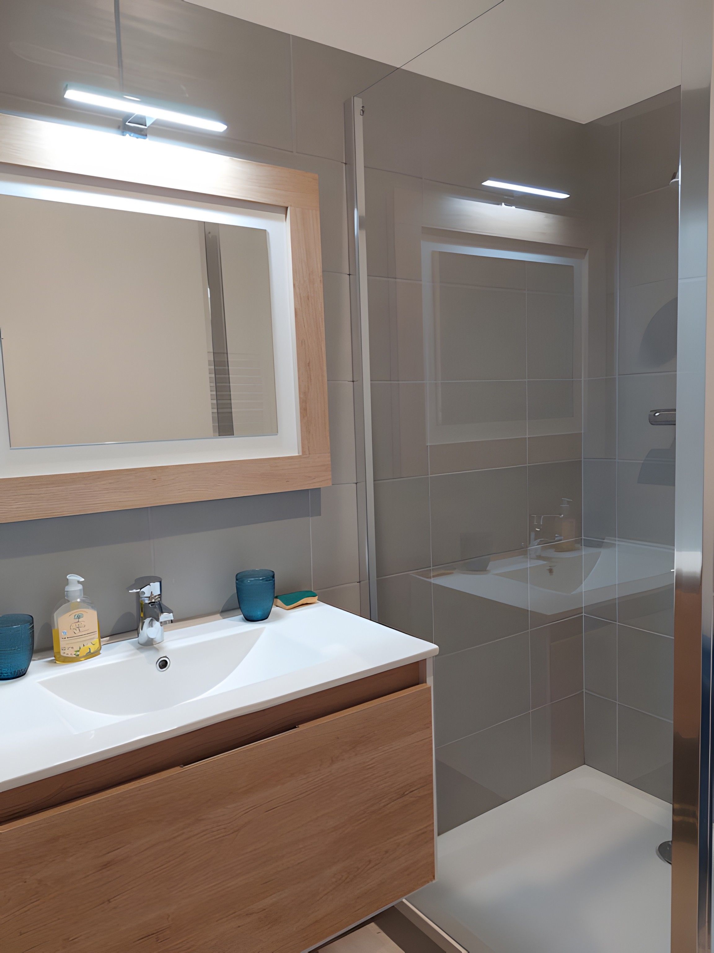 A modern bathroom with a wooden vanity, two sinks, a large mirror, and a shower area.