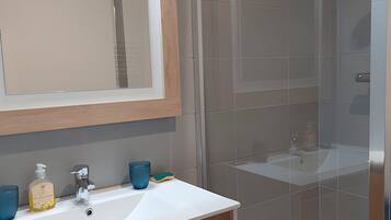 A modern bathroom with a wooden vanity, two sinks, a large mirror, and a shower area.