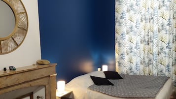 Une chambre à coucher avec un lit, des lampes de chevet, une commode, un miroir et un rideau à motifs.
