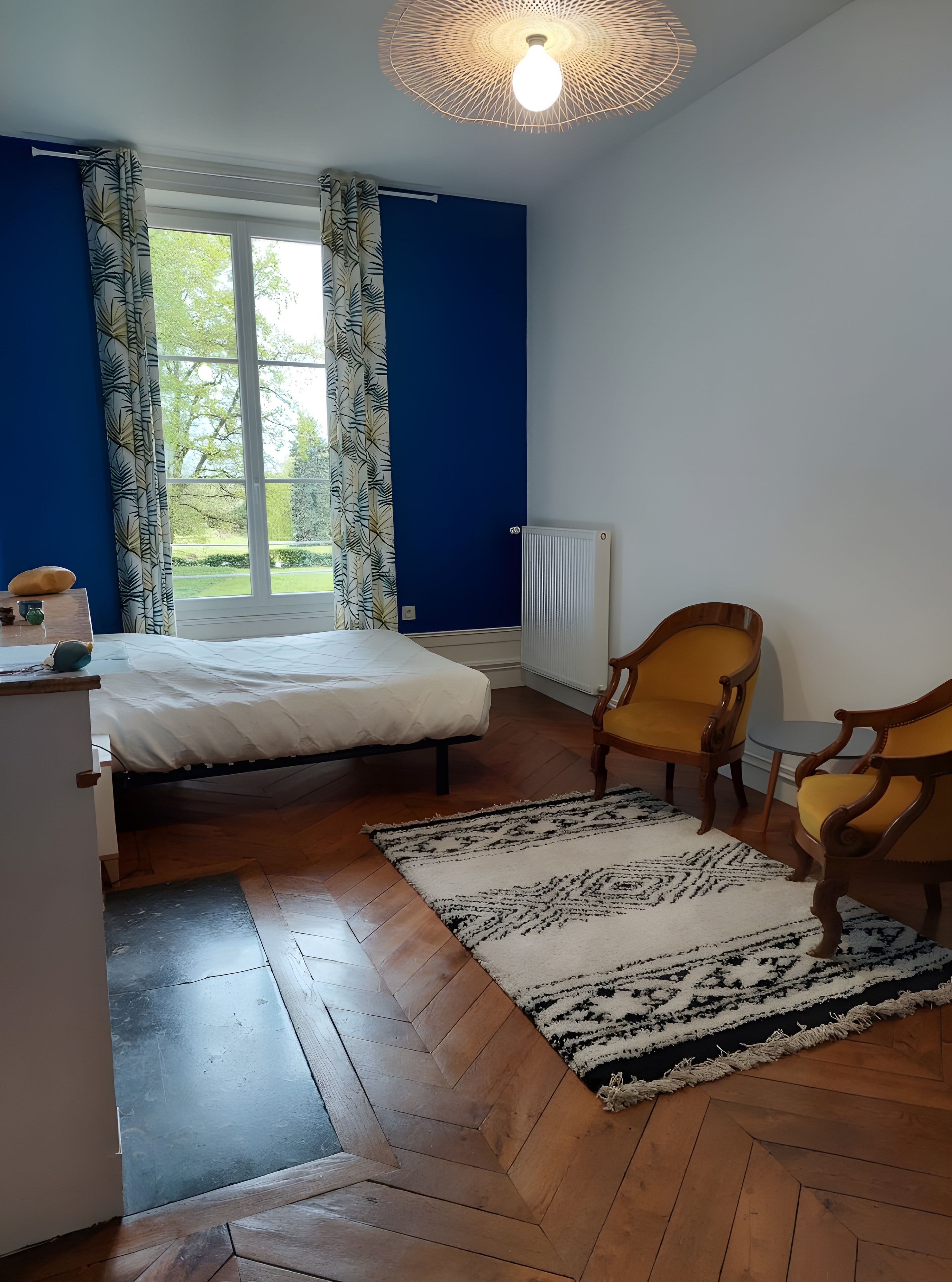 Une chambre à coucher avec un lit, une chaise, un radiateur et une fenêtre.