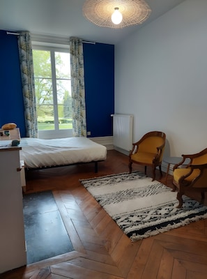 A bedroom with a bed, a chair, a radiator, and a window.