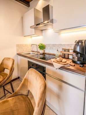Eine moderne Küche mit Einbauherd, einer Kaffeemaschine und einem Blumentopf.