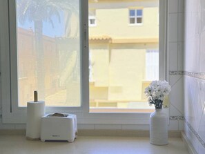 A room with a window, a white radiator, and a vase with white flowers. - Vibes Center Flat - El Mirador (Tarifa)