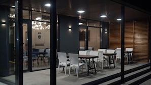 An indoor seating area with tables and chairs, glass walls, and a ceiling with recessed lighting. - Gastello Yard (Bishkek)