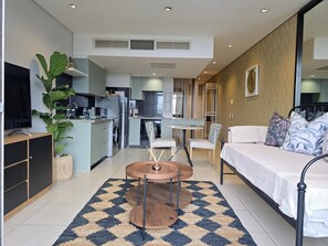 Un appartement moderne comprenant une cuisine, un coin repas et un salon avec un lit.