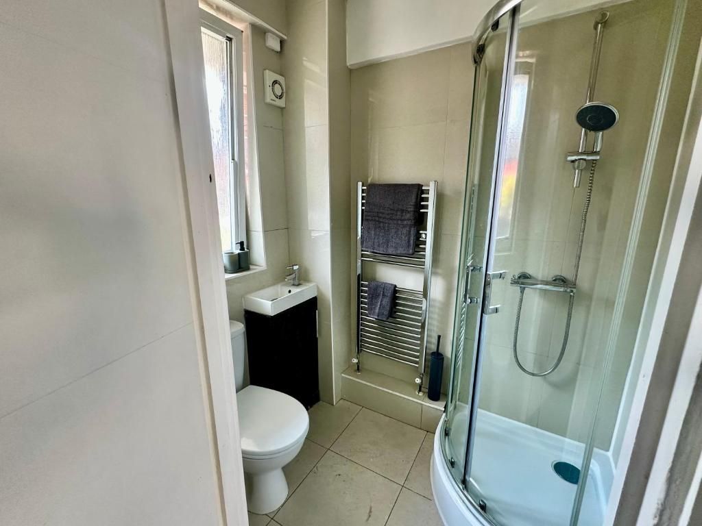 A bathroom with a toilet, sink, and glass-enclosed shower.