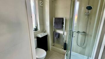 A bathroom with a toilet, sink, and glass-enclosed shower.
