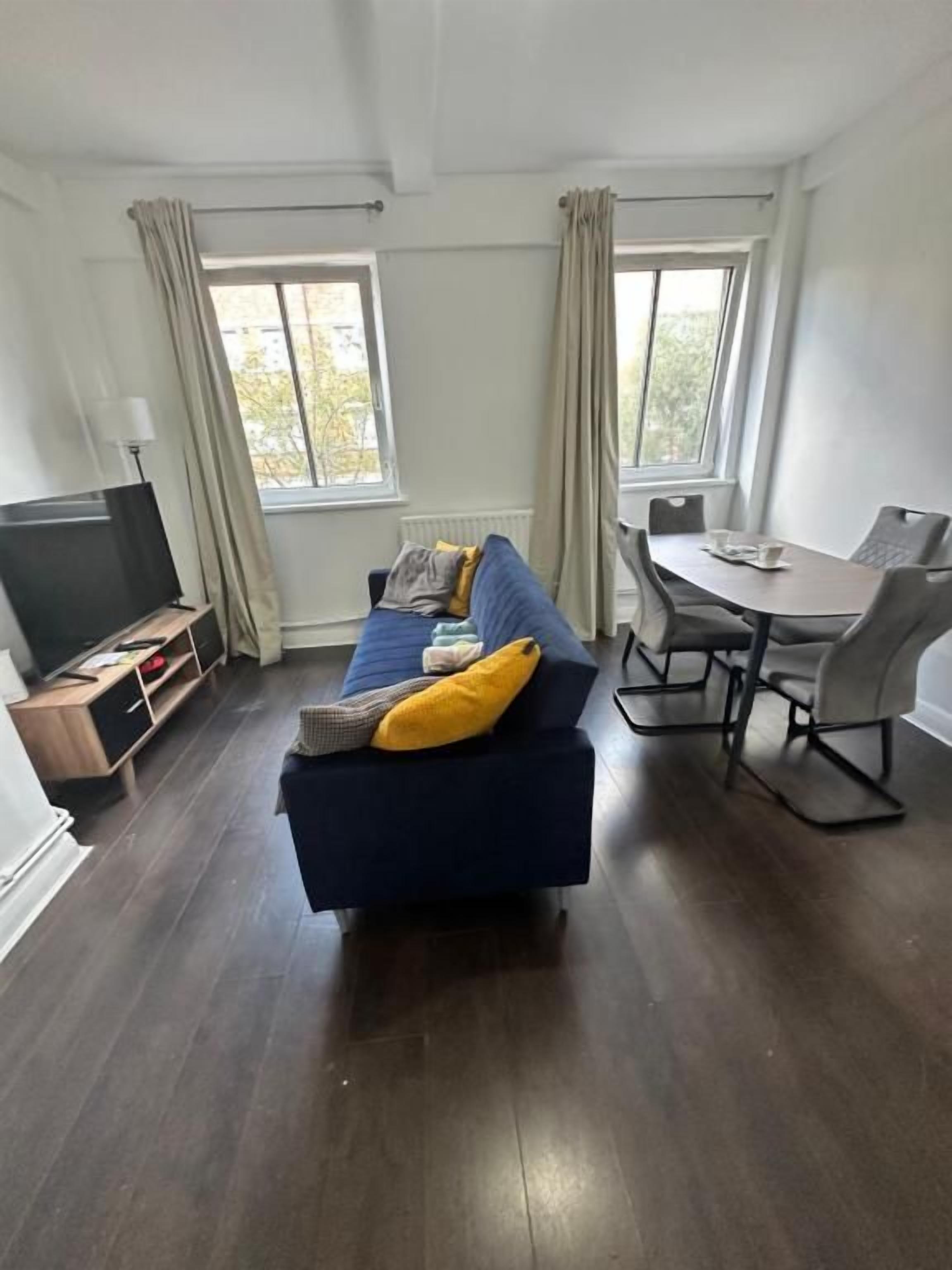A living room with a sofa, a dining table, and a TV.