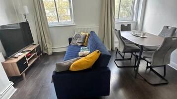A living room with a sofa, a dining table, and a TV.