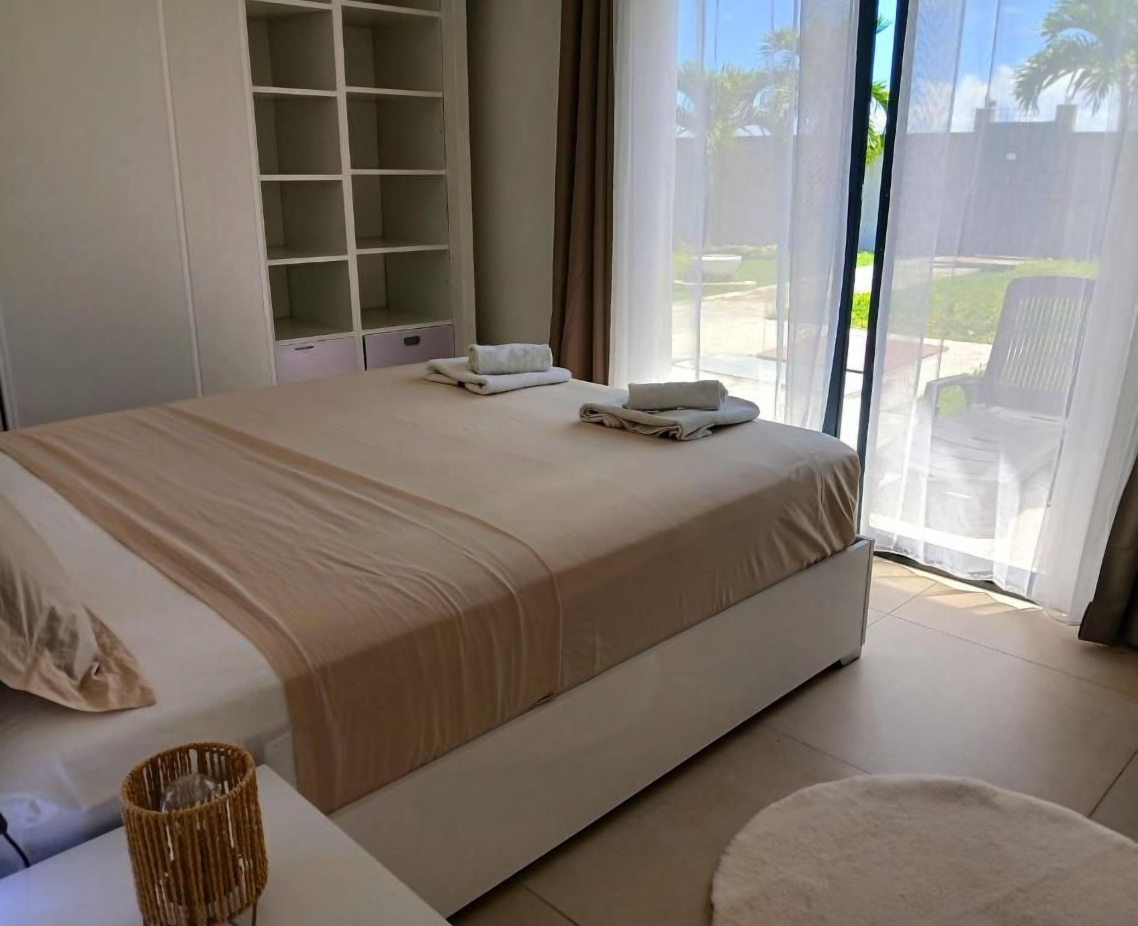 Une chambre avec un lit, une armoire, une fenêtre donnant sur un beau paysage et une chaise.
