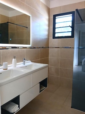 Een moderne badkamer met een grote spiegel, twee wasbakken en een douchehoek.