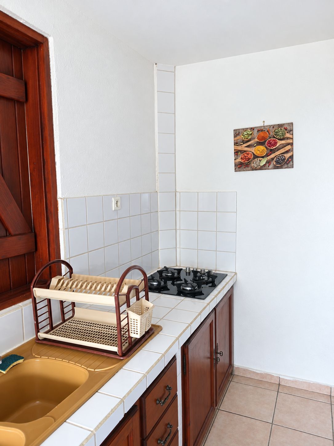 A kitchen with a stove, sink, and wooden cabinets.