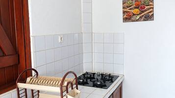 A kitchen with a stove, sink, and wooden cabinets.
