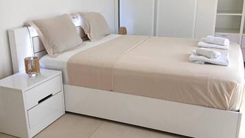A bedroom with a bed, nightstand, and a round rug.