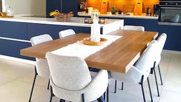 A modern kitchen with dark blue cabinets, a wooden island, and a dining area with a wooden table and chairs.