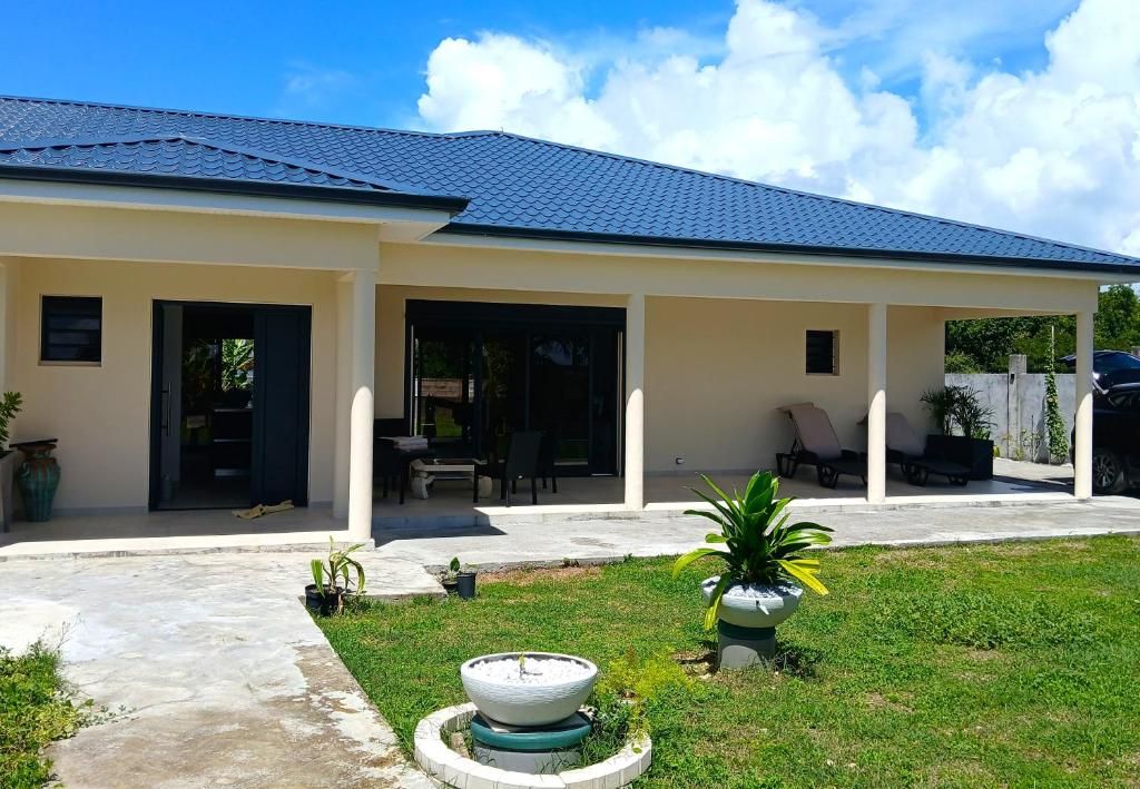 Une maison à deux étages dotée d’un patio couvert, d’une pelouse et d’un élément décoratif aquatique.