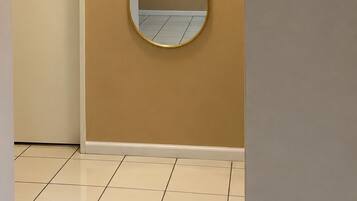 A hallway with a door, a wall-mounted mirror, and a ceiling light fixture.
