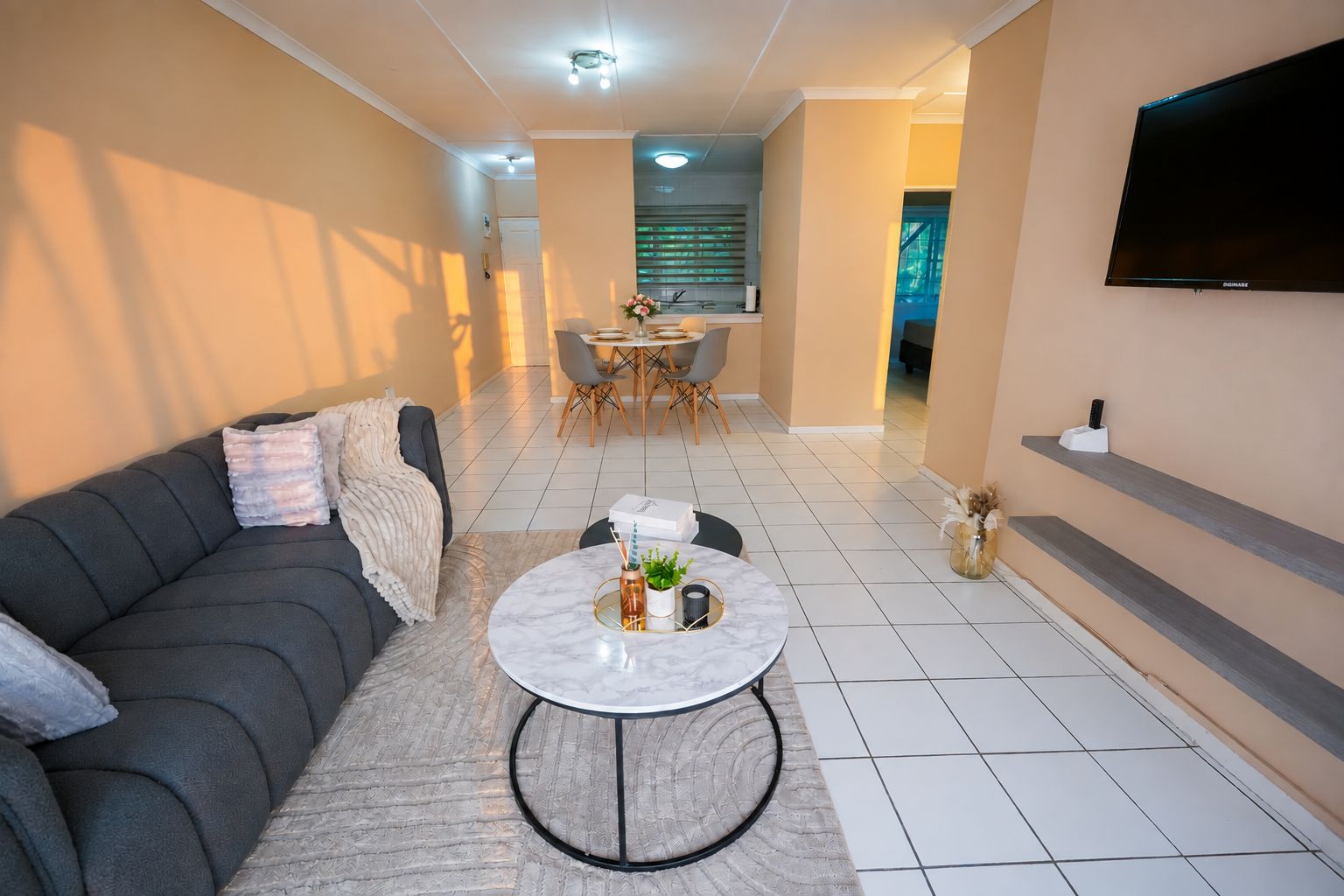Un salon moderne avec un canapé, une table basse ronde et un coin repas comprenant des chaises et une table.