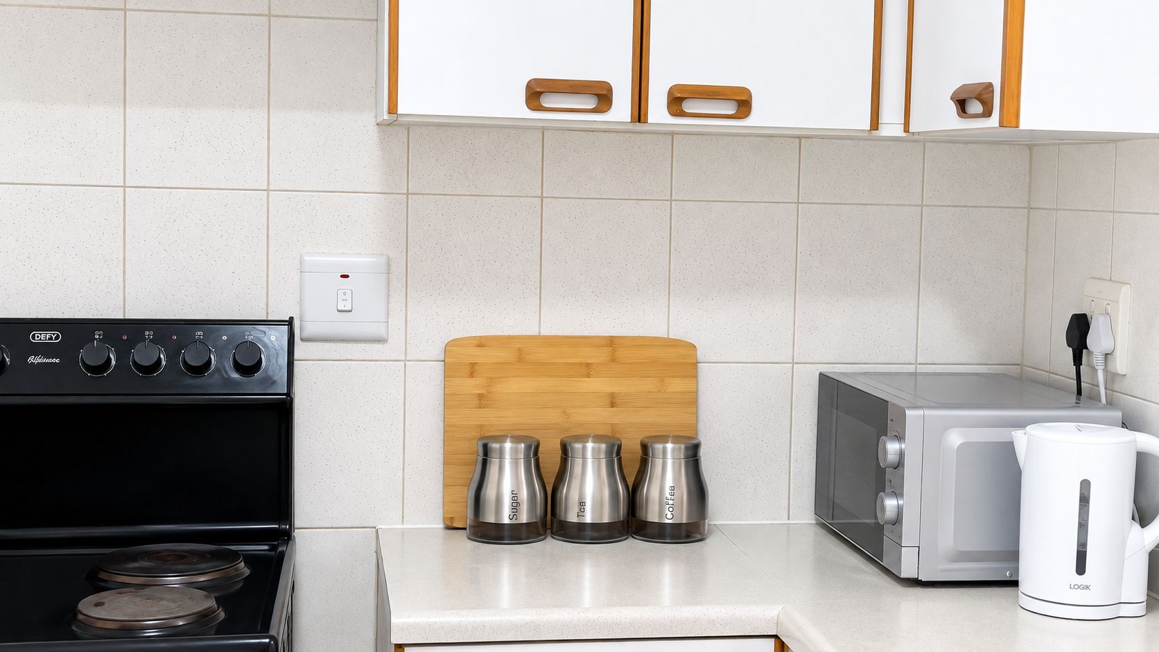Una cucina con un piano cottura nero, un forno a microonde, un tostapane e una macchina per il caffè.