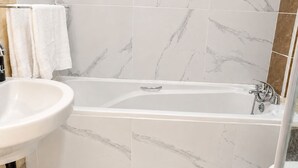 Un bagno con una vasca, un lavandino e una zona doccia.