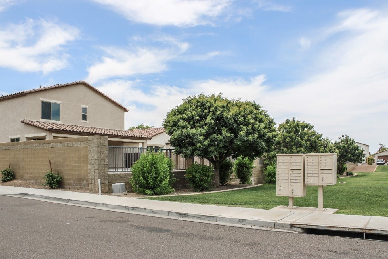 A residential area with a house, a tree, a mailbox, and a clear sky.