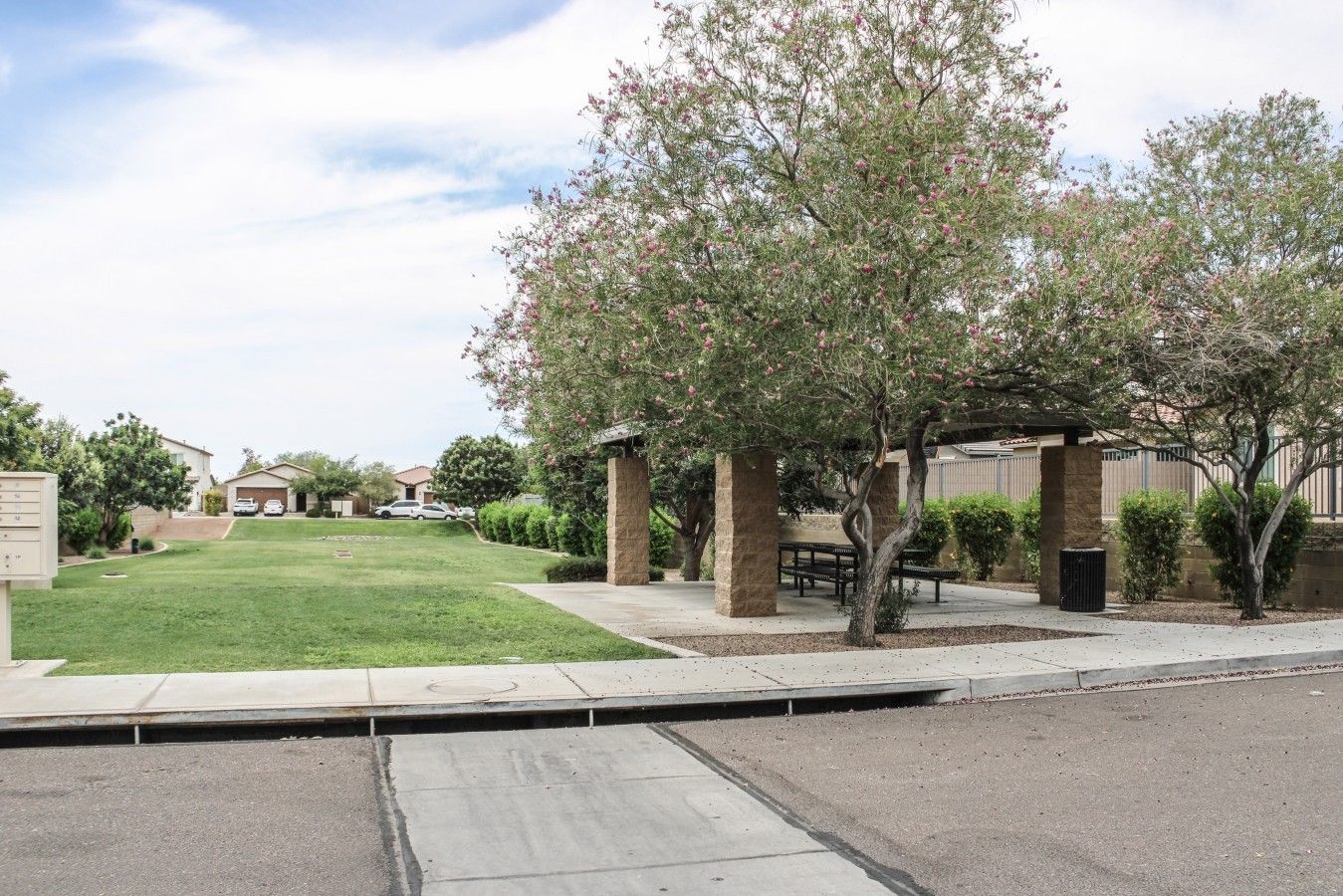 A residential area with a well-maintained lawn, a gazebo, and a row of houses in the background.