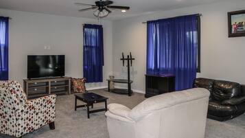 A living room with a television, a sofa, a coffee table, and a fireplace.