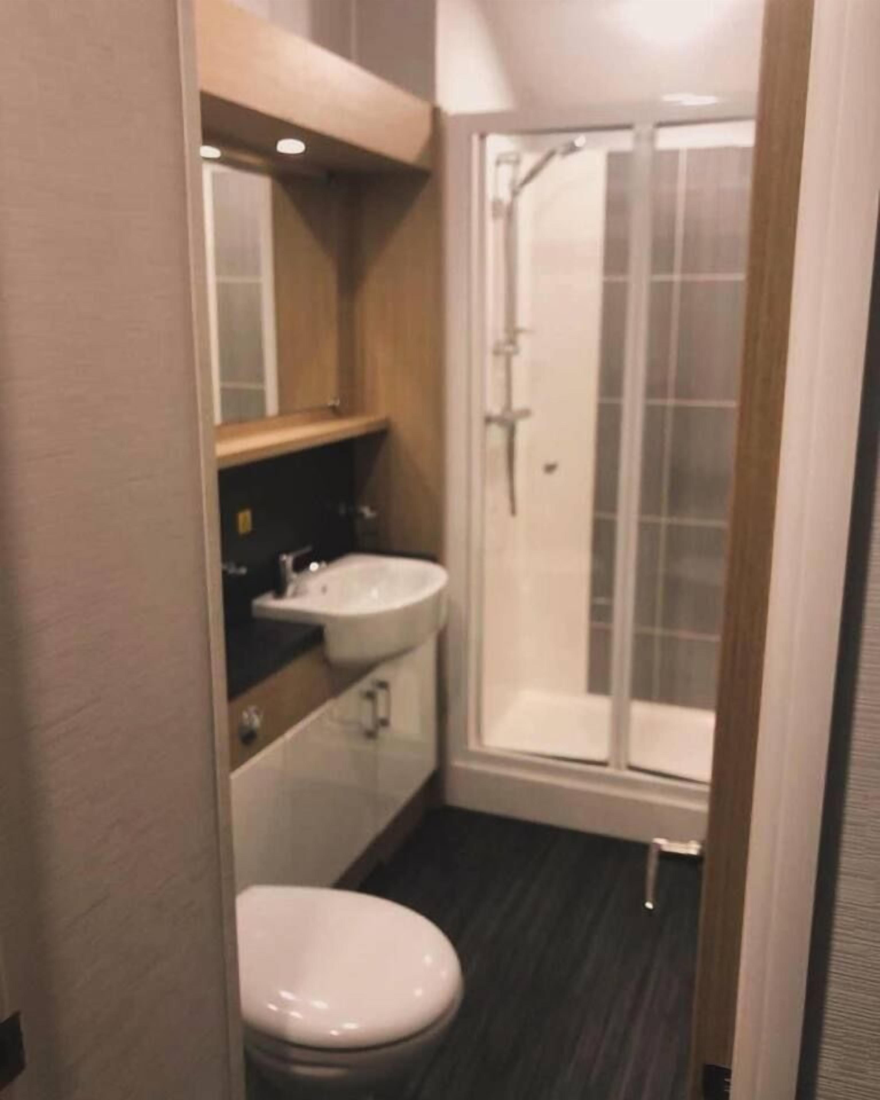 A compact bathroom with a toilet, a sink, and a glass-enclosed shower.