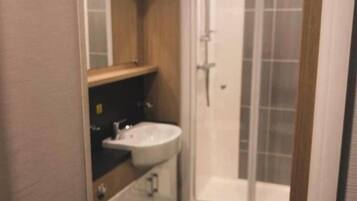 A compact bathroom with a toilet, a sink, and a glass-enclosed shower.