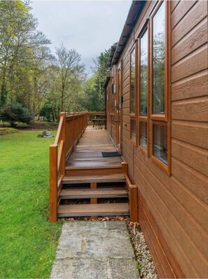 A wooden exterior with a stone pathway leading to a wooden deck.