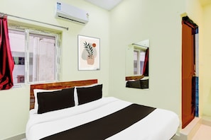 A hotel room with a bed, a window with curtains, an air conditioning unit, a framed artwork, and a mirror. - Super Hotel O Moula Ali Neredmet (Hyderabad)