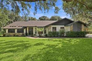 A single-story house with a covered porch, a stone foundation, and a well-maintained lawn. - Lakeland 4br Vacation Home Sleeps 9 Pool 4 Bedroom Home (Lakeland)