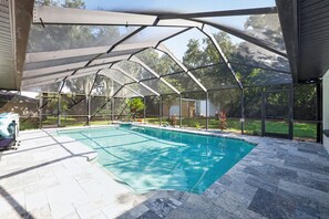 Ein überdachter Außenpool mit freiem Blick auf den umliegenden Garten und die Bäume.