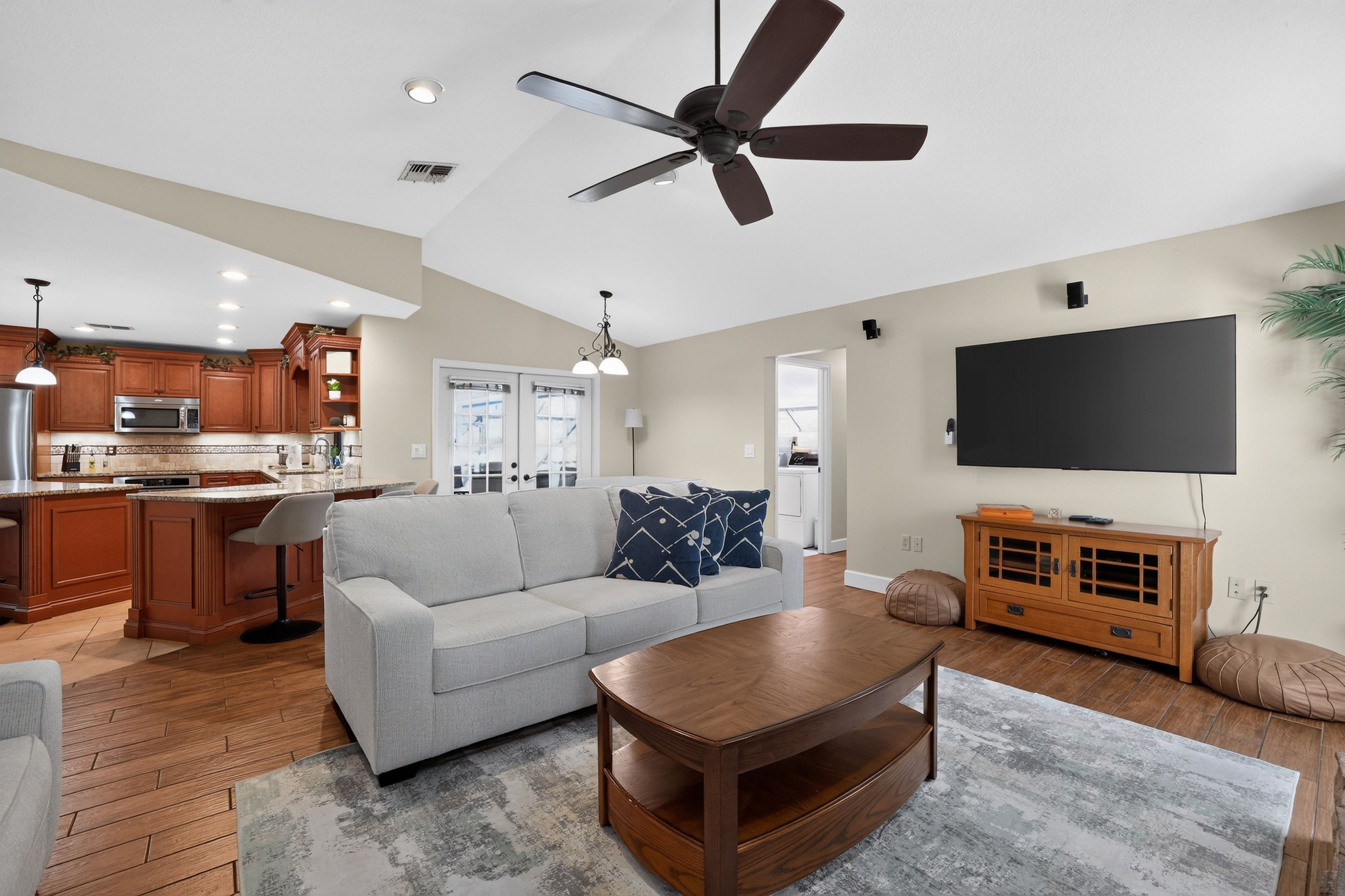 A modern living room with a grey sofa, wooden coffee table, and a ceiling fan.