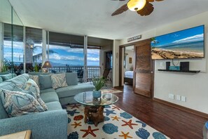 A modern living room with a large glass table, a sofa set, and a starfish-patterned rug. - Maalaea Kai #220 2 Bedroom Condo (Wailuku)